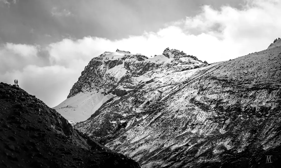 Black and white ridge with two tiny climbers on the skyline